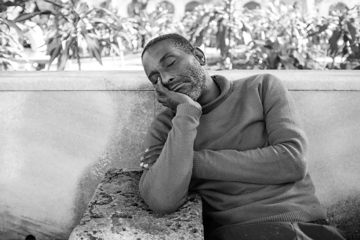 Une personne endormie sur un banc. l Source : Getty Images