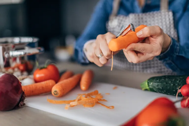 Une femme nettoyant des carottes | source : Getty images