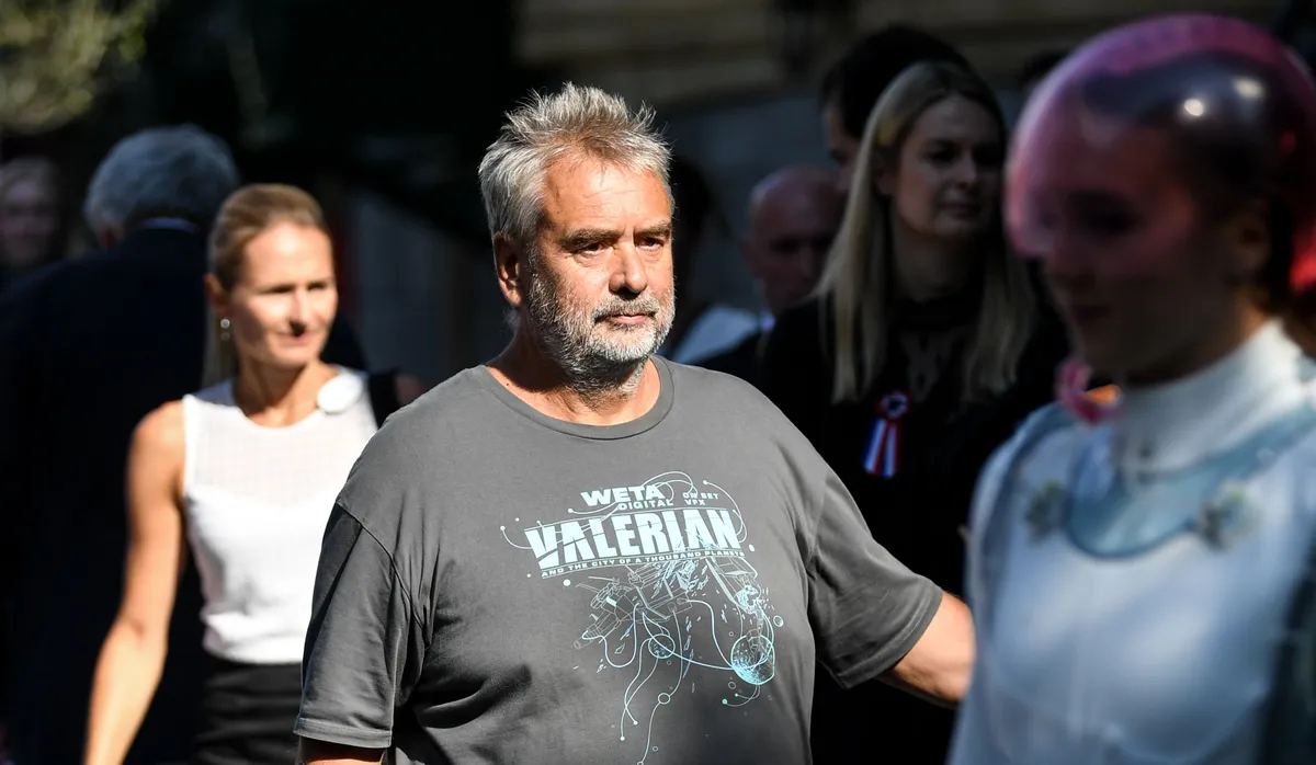 Luc Besson se tient à côté d'un employé du parc déguisé. | Photo : Getty Images