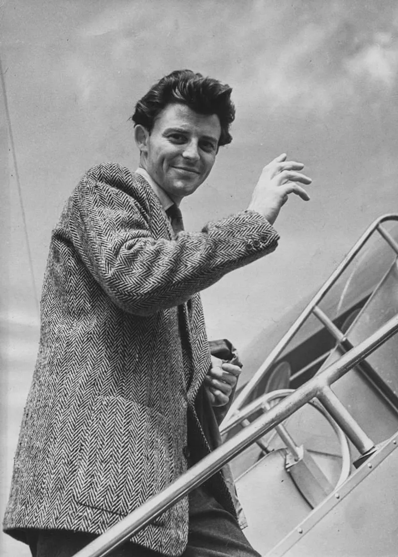L'acteur français Gérard Philipe agitant la main alors qu'il monte à bord d'un avion à destination de Rome, où il commencera le tournage de "La beauté et le diable", le 14 juillet 1949 | Source : Getty Images.