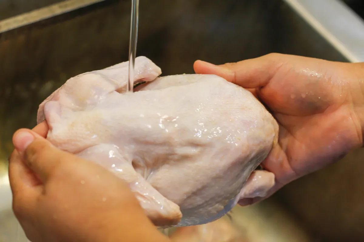 Une femme qui lave du poulet cru. | Photo : Getty Images