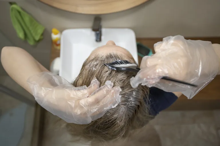 Une femme appliquant des teintures sur ses cheveux. | Photo : Getty Images