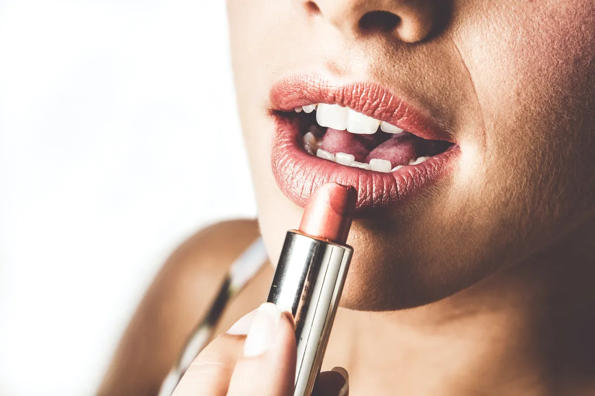 Une femme utilisant du rouge à lèvres. l Source : Unsplash