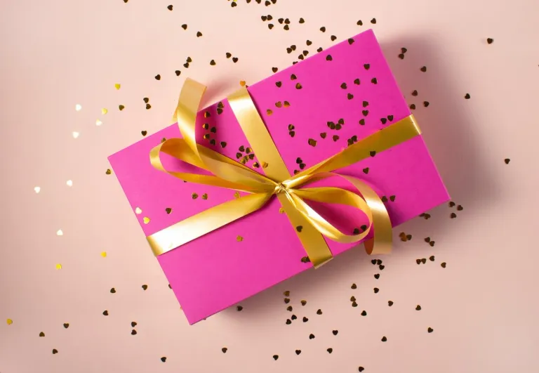 Cadeau emballé dans une feuille rose avec un ruban doré | Source : Unsplash