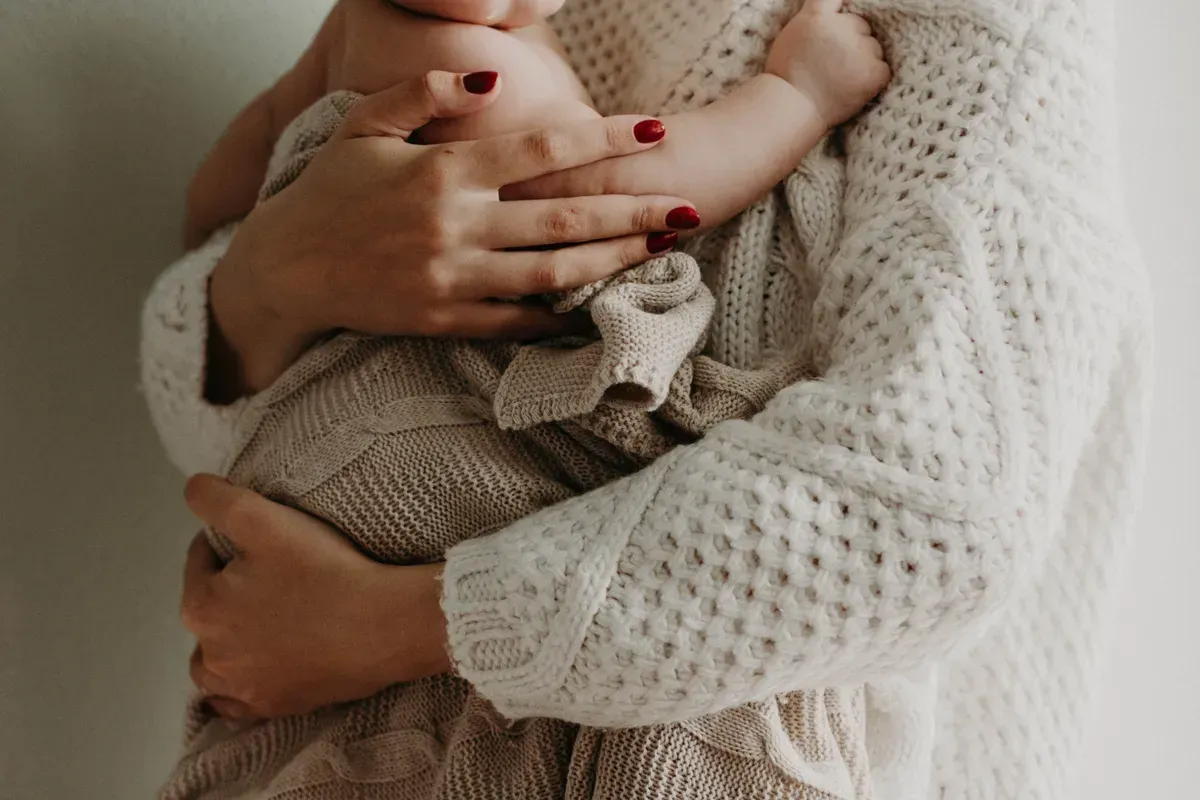 Une femme tenant un bébé dans son bras. | Photo : Pexel
